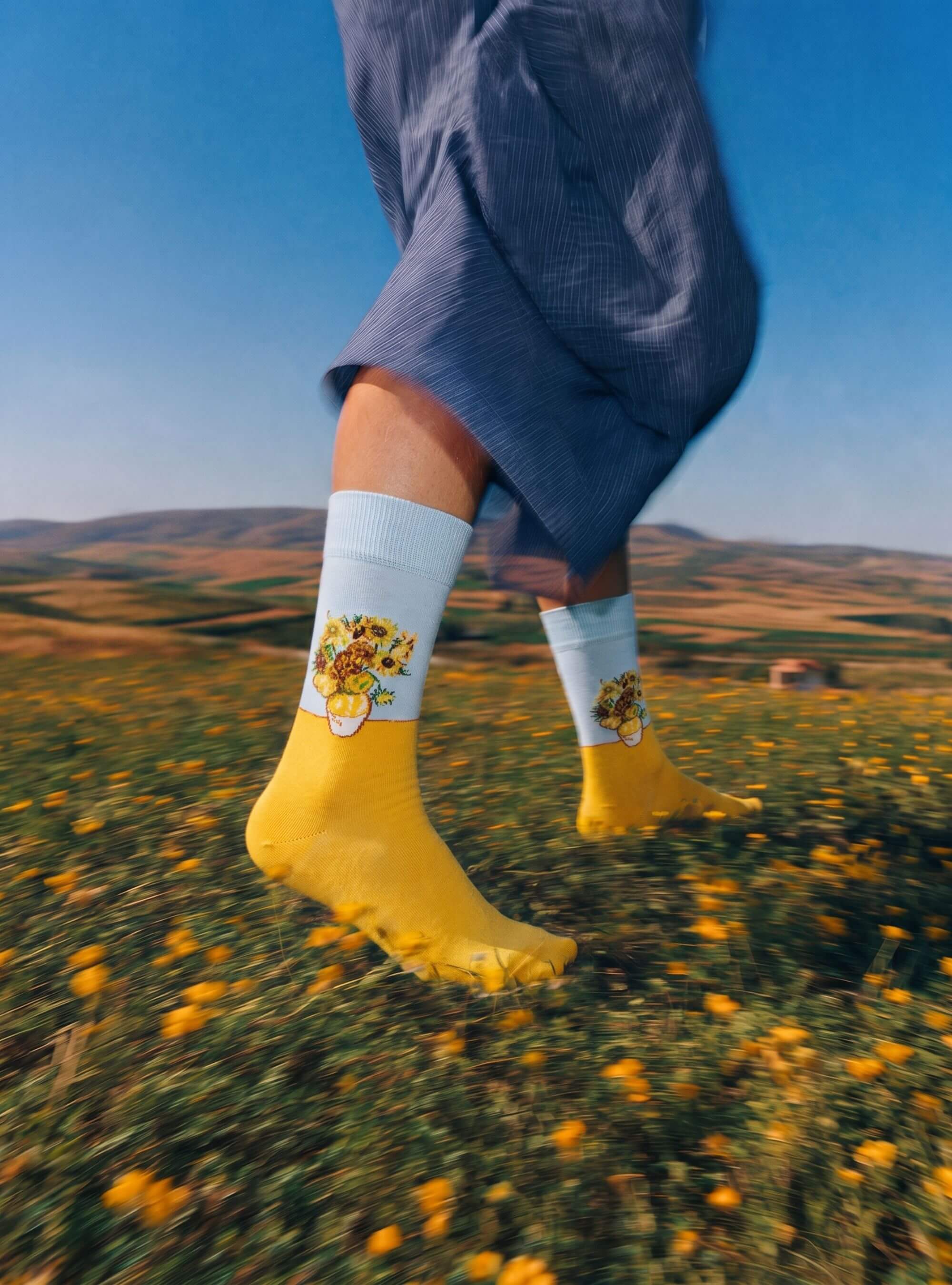 Zonnebloemen kunstsokken van Vincent van Gogh gedragen in een veld met gele bloemen